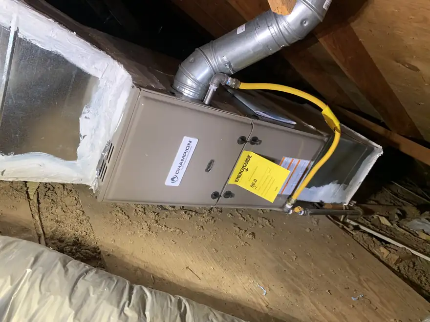 A gas furnace in an attic with its yellow gas supply line and flue connected