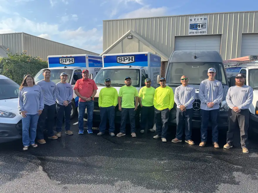 The Stith Plumbing & HVAC crew standing in front of their branded box trucks at the Springdale shop